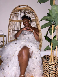 a woman in a white dress sitting in a wicker chair